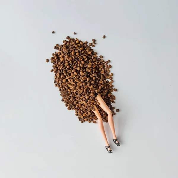 少女人形の足がコーヒー豆の山から出てきた 創造的なコーヒー飲み物概念 ユニークなフラット レイアウト — ストック写真