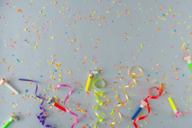 Renkli parti şeritleri ve pastel gri arka planda konfeti ile yapılmış yaratıcı bir kompozisyon. Düz konsept kutlaması.