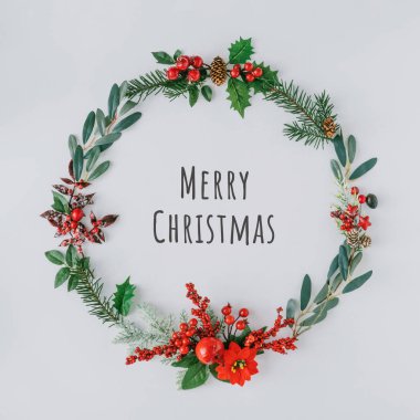Doğal kış şeylerinden yapılmış Noel yuvarlak çerçevesi Mutlu Noeller yazılı 