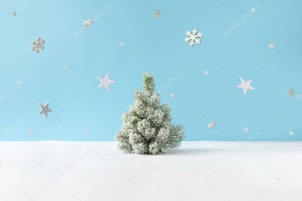 Creative layout with snowy Christmas tree and stars with snowflakes on bright blue background. Minimal winter nature holiday scene. 