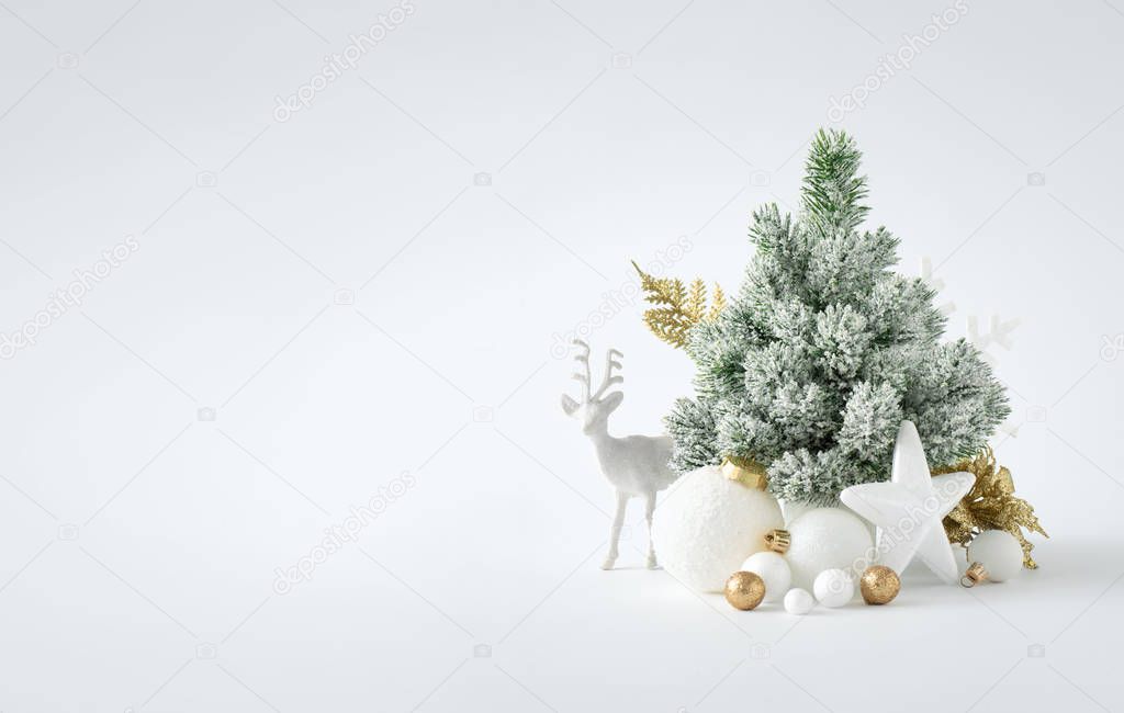 New Year layout with white snowy Christmas tree and deer toy with golden Christmas decorations 