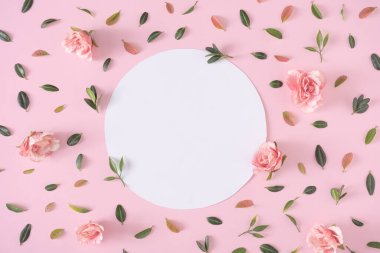 Creative layout pattern with green and red leaves and flowers with circle shaped paper card note on pink background. Minimal spring concept 