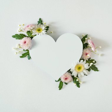 Heart shaped paper card note with natural spring wildflowers. Women day minimal concept 