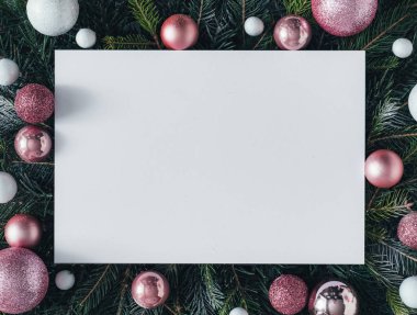 Natural composition with Christmas tree branches and pink baubles with paper card note . Holiday concept.