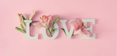 Spring flowers with word Love on pastel pink background. valentines day concept