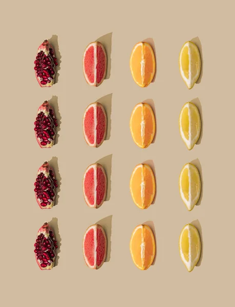 Minimal nature pattern with grapefruit and orange with pomegranate and lemon slices on pastel sand background. Summer fruit concept.