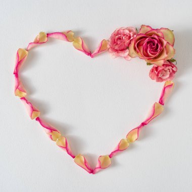 Gül yaprakları ve pembe çiçeklerden yapılmış yaratıcı bir düzen. Asgari doğa aşk geçmişi. Bahar çiçekleri kavramı.