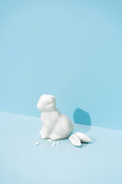 Kulakları kırık bir Paskalya tavşanı. Minimal pastel pembe ve mavi Paskalya bayramı konsepti. Çağdaş biçim.