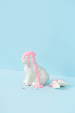 Kulakları kırık bir Paskalya tavşanı. Minimal pastel pembe ve mavi Paskalya bayramı konsepti. Çağdaş biçim.
