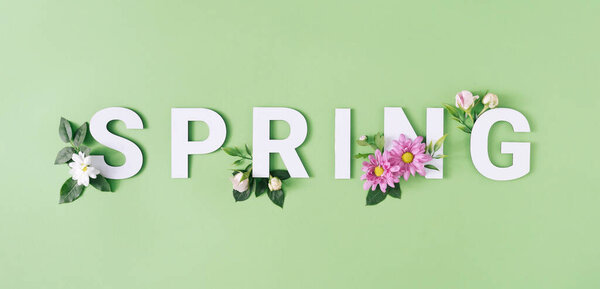 Весенние буквы с белыми и розовыми цветами на зеленом фоне. Минимальная концепция сезона природы
.