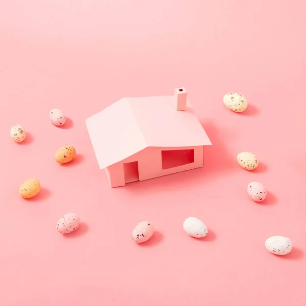 Easter eggs arround pink house. Spring nature concept. Easter holiday background idea.