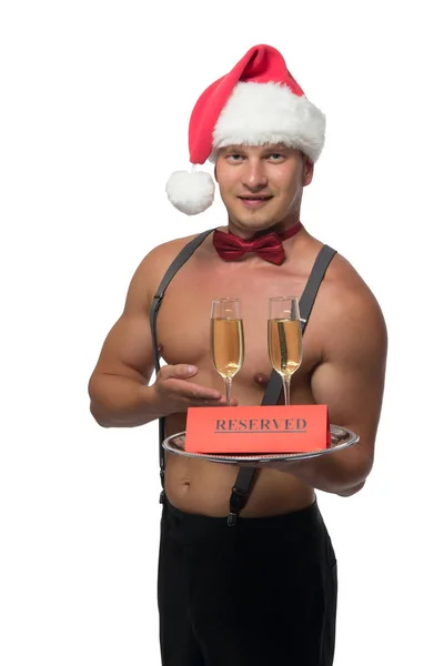 Camarero con un torso desnudo en el sombrero de Santa Claus sosteniendo copas de champán —  Fotos de Stock