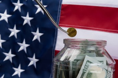 metal forseps bayrak arka plan üzerinde para ile bir kavanoz bozuk para koymak