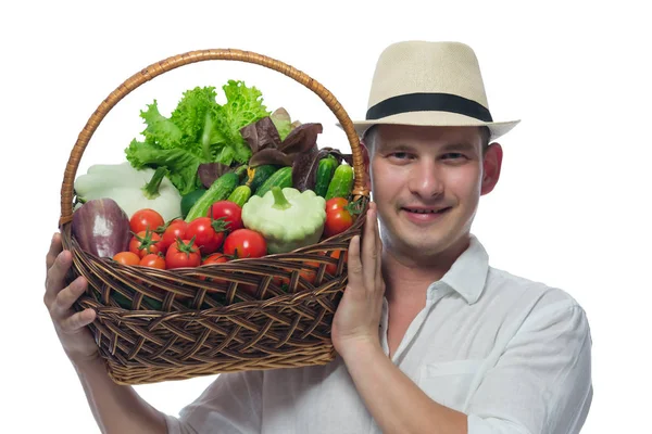 Rolnik w kapeluszu i białej koszuli nosi na ramieniu koszyka warzywa — Zdjęcie stockowe