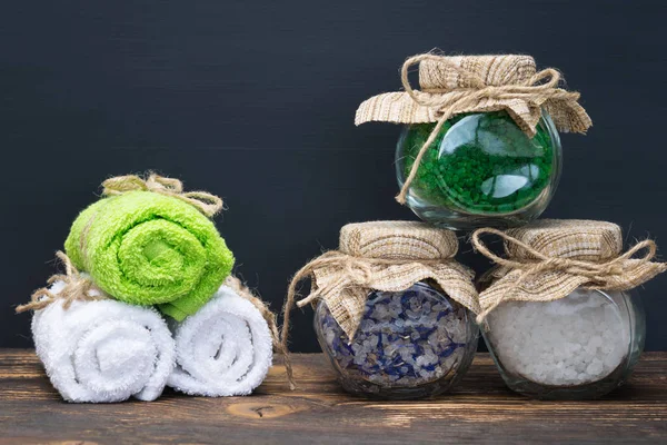 Schöne gefaltete Handtücher für den Wellnessbereich und Salz im Glas auf dem Tisch — Stockfoto