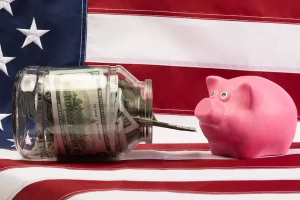 Hij bank met het geld voor een roze varken op de achtergrond van de vlag van de Verenigde Staten — Stockfoto