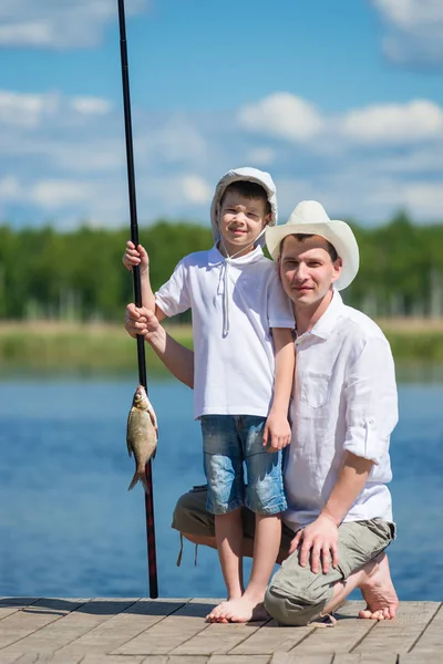 Baba ile oğlu doğada kıyıdan olta kamışı bir balık yakaladı — Stok fotoğraf