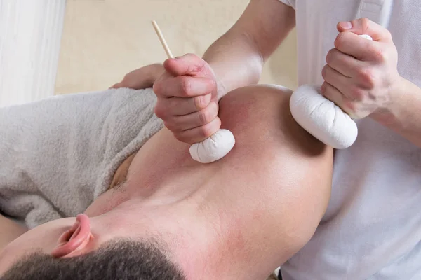 Man doet schouder massage met kruiden zakken, close-up — Stockfoto