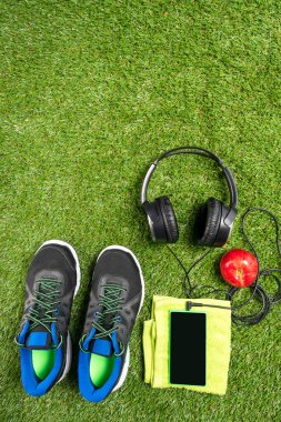 müzik ve yeşil çim bir arka plan üzerinde kırmızı elma ile spor ayakkabı