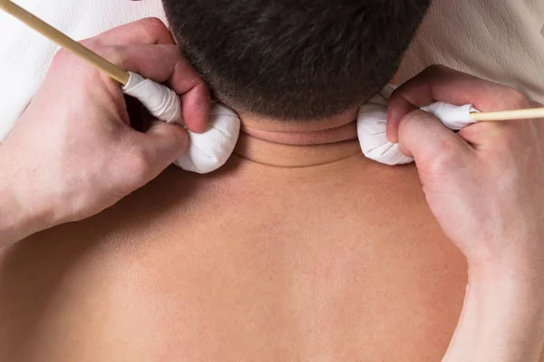 Two hands make a neck massage with herbs in the bag — Stock Photo, Image