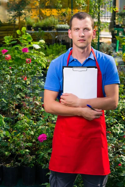 Caucasian man is taking notes in a flower greenhouse — Stock Photo, Image