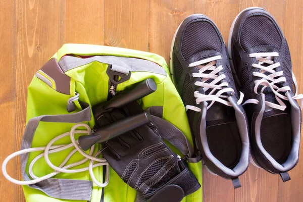 Saco verde para coisas esportivas em um fundo de madeira e sapatos — Fotografia de Stock