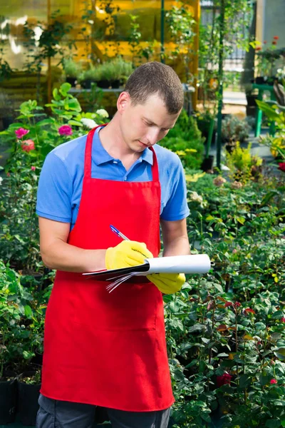 The man keeps a register of plants in the garden — Stock Photo, Image