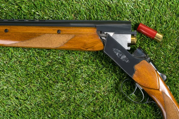 Rifle de caza con un cartucho rojo se encuentra en la hierba — Foto de Stock