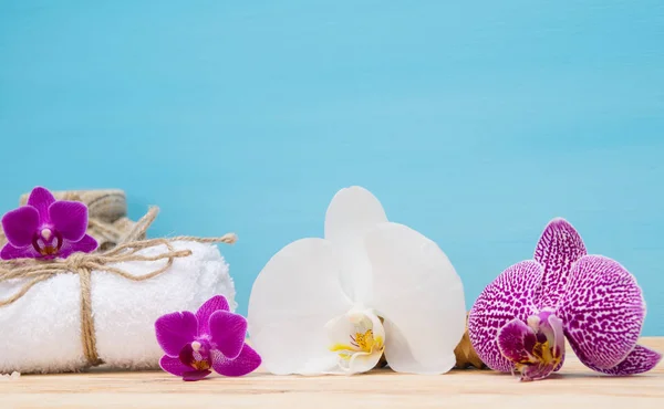 Weißes Handtuch und weiße Orchidee auf blauem Hintergrund — Stockfoto