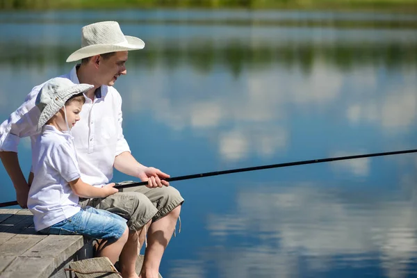 Vader en zoon zijn zittend op de pier en vissen op de rivier — Stockfoto