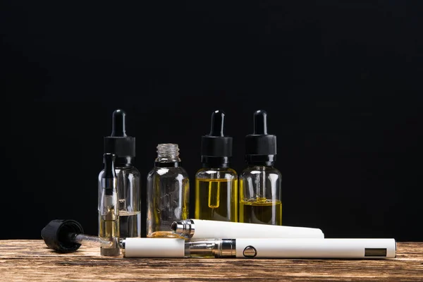 Elektronisk cigarett med smaker ett par i flaskan på bordet med en svart bakgrund — Stockfoto