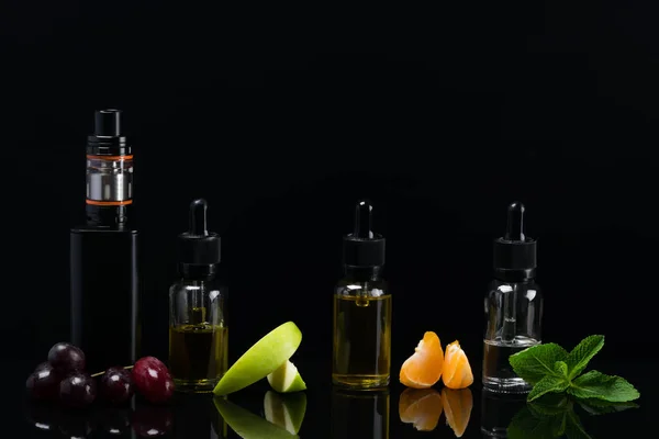 Fruchtaromen in Flaschen für eine elektronische Zigarette auf schwarzem Hintergrund — Stockfoto