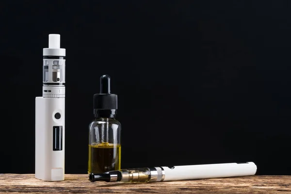 Elektronisk cigarett och en flaska med doft, konceptet på en träskiva — Stockfoto