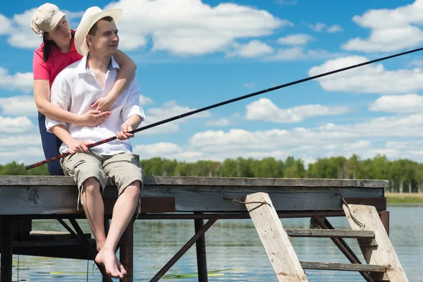 Жена обнимает мужа на рыбалке, когда он ловит рыбу. — стоковое фото