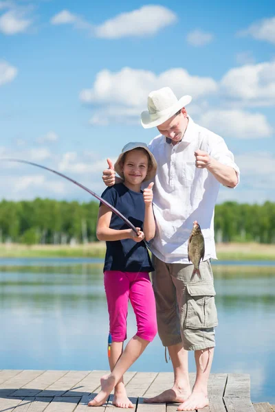 Chica y un padre de vacaciones atrapado un pez en un aparejo de pesca en el río —  Fotos de Stock