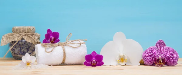 Weißes Handtuch mit dem Duft von Orchideen auf dem Tisch — Stockfoto