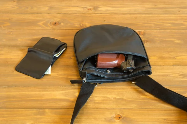 Bag with a gun and purse with money lies on a dark table