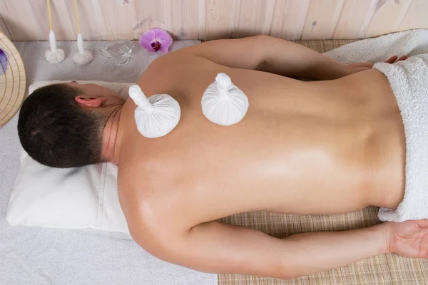 Massage met kruiden zakken man voor een gezonde rug — Stockfoto