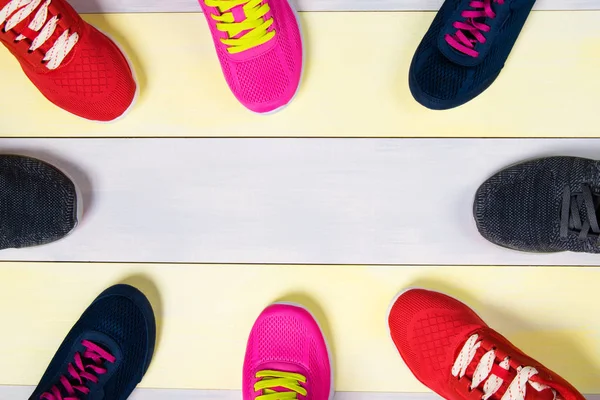 Sapatos de esportes espalhados em um soalho multicor, no meio há um lugar de inscrições — Fotografia de Stock