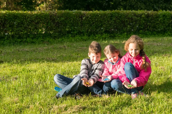 Tre tonåringar sitter njuter i gräset som spelar i spinner — Stockfoto
