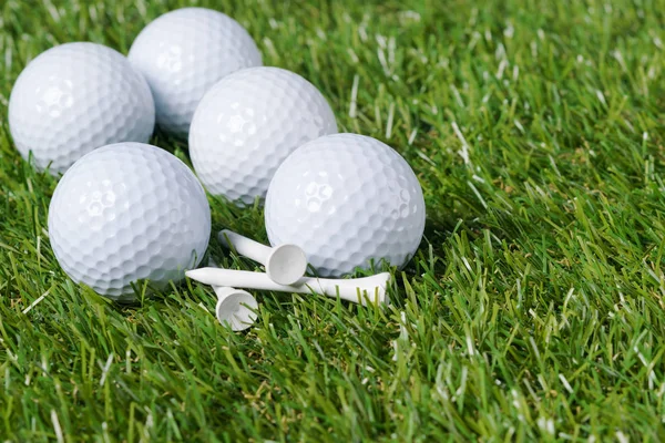 Білі м'ячі для гольфу лежать на купі зеленої трави — стокове фото