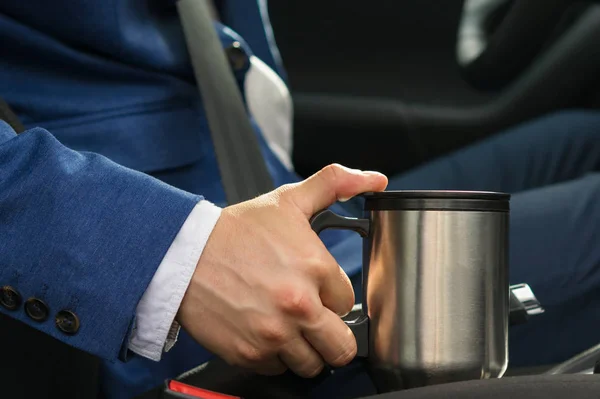 O motorista no carro leva uma caneca térmica com uma barra de café para não adormecer ao volante — Fotografia de Stock