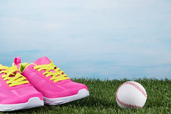 Zapatillas rosadas con cordones amarillos en la hierba cerca de la pelota —  Fotos de Stock