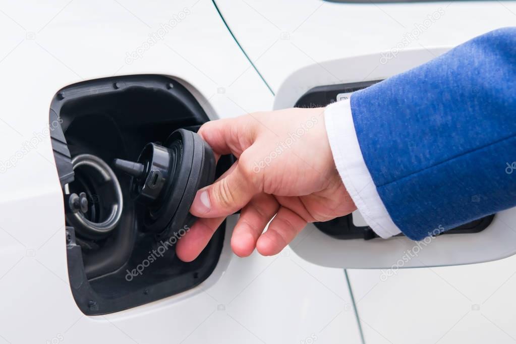 Open the lid of the fuel tank in the car. Vehicle refueling at a gas station businessman in a suit