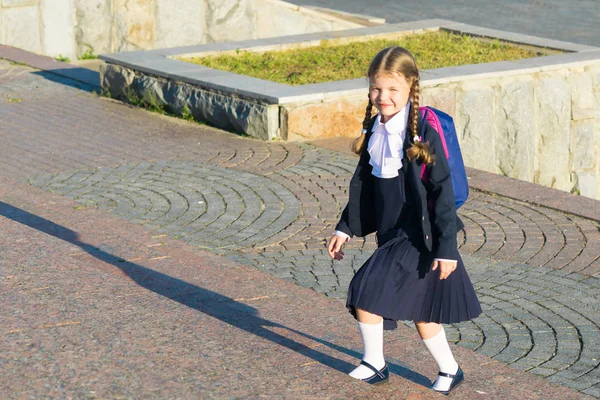 Kız okulda bir sırt çantası ile Tekdüzen bir merdiven yükselir