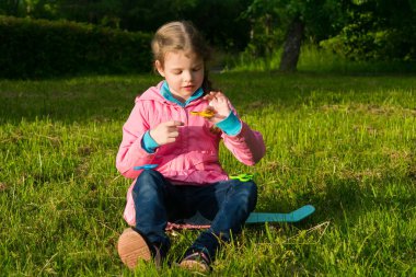 Küçük kız bir spor tahta üzerinde oturan ve bir spinner iplik