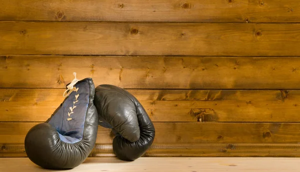 木製の壁の背景に対して、床にボクシングの手袋 — ストック写真