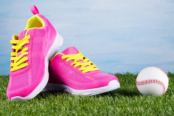 Zapatillas deportivas rosadas sobre fondo azul junto a una pelota de béisbol —  Fotos de Stock