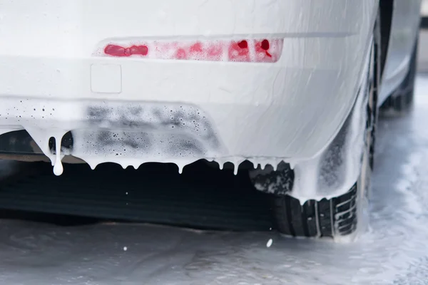 The contactless foam for washing the machine flows down the car's bumper — Stock Photo, Image