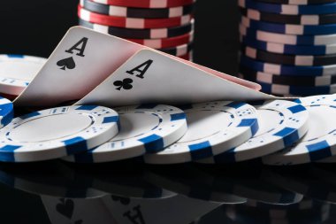 Karanlık bir arka plan üzerinde poker oynamak için cips iskambil kartları iki as yalan